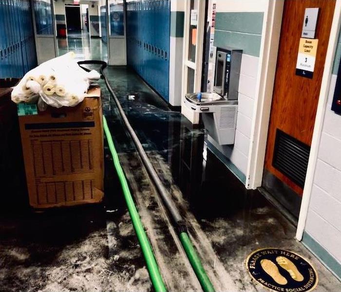 School floor with black oil and SERVPRO cleanup equipment