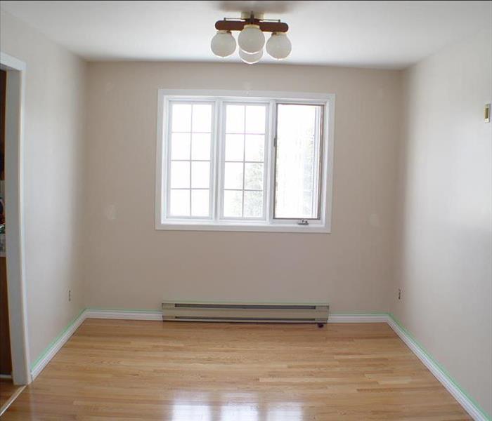 A room with no furniture, 3 windows on the far wall, white walls no draperies, and a 3 lamp light fixture