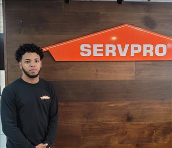 Pedro posing in a black SERVPRO shirt by our sign