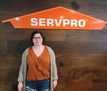 Female employee posing in front of SERVPRO sign wooden wall